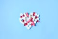 White and red various pills and capsules in heart shape on blue Royalty Free Stock Photo