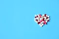 White and red various pills and capsules in heart shape on blue Royalty Free Stock Photo