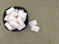 White refined sugar lumps, cubes, in bowl on fabric background with copyspace.