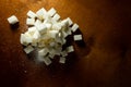 cubes of white unrefined sugar on a wooden background with light reflections