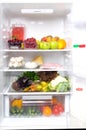 In a white refrigerator, on the top shelf fruits, berries and a jug with compote, on medium mushrooms, poultry meat, cottage