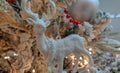 White reindeer figure decoration on Christmas tree with red pearls, decorative balls and cozy yellow lights Royalty Free Stock Photo