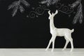 White reindeer on wooden table over chalkboard background whith hand drawn chalk illustrations. Royalty Free Stock Photo