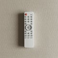 White remote control on a textured beige surface. The remote features several circula Royalty Free Stock Photo