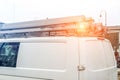 White repair and service van with ladder and orange light bar on roof at city street. Assistance or installation team vehicle Royalty Free Stock Photo