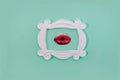 A white retro frame with women lips wearing red lipstick on pastel green background. Creative design for hypster Valentine card or Royalty Free Stock Photo