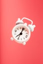 White retro style alarm clock in levitation isolated on pink background Royalty Free Stock Photo