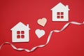 White ribbon and decorative hearts between two house models symbolizing connection in long-distance relationship on red background