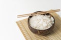 White rice in a coconut bowl on a white background. Minimalistic photo with rice and bamboo chopsticks Royalty Free Stock Photo