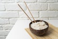 White rice in a coconut bowl on a white background. Minimalistic photo with rice and bamboo chopsticks Royalty Free Stock Photo