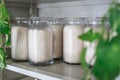 White rice in glass jars on wooden shelves in a light vintage Cabinet, green vines and plants hanging Royalty Free Stock Photo