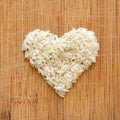 White rice grains in heart shape on wooden cutting board, in square format for social media, banners, and backgrounds. Royalty Free Stock Photo