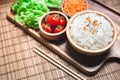 A white rice in wooden bowl and chopsticks with carrots, black sesame , and tomatoes vegetables on wooden board. Healthy food and Royalty Free Stock Photo