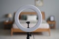 White ring light on black tripod in bedroom, diffusion dome framing blurred bed Royalty Free Stock Photo