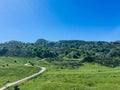 White road passing through green meadow is leading to the mountains of Covadonga Royalty Free Stock Photo