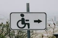 White Road sign disabled, with black icon man in wheelchair and right arrow. Accessible environment in urban space Royalty Free Stock Photo