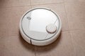 white Robot vacuum cleaner cleaning dust on tile floors in kitchen. Modern smart cleaning technology housekeeping Royalty Free Stock Photo