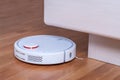 White robot vacuum cleaner runs in bedroom