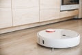 White robotic vacuum cleaner cleaning floor in modern kitchen Royalty Free Stock Photo