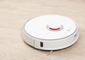 White robotic vacuum cleaner on the floor cleaning dust in the r