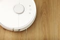 White robotic vacuum cleaner on laminate floor cleaning dust in living room interior. Smart electronic housekeeping Royalty Free Stock Photo