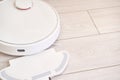 White robotic vacuum on light wood floor for efficient automated cleaning Royalty Free Stock Photo