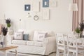 White room interior with couch with pillows, posters on wall, dining table with chairs and fresh lavender in the real photo Royalty Free Stock Photo