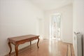 White room with wooden table in renovated apartment, sunlight