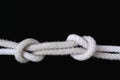 A white rope tied with fisherman knot on black background