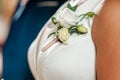 White rose bonbonniere on the white dress of the bride