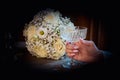 White rose bridal bouquet on the table. The bride is holding a crystal glass