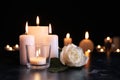 White rose and burning candles on table in darkness