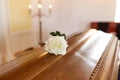 White rose flower on wooden coffin in church