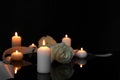 White roses and burning candles on black mirror surface in darkness, space for text. Funeral symbols Royalty Free Stock Photo