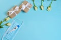 white roses medical mask thermometer gifts in craft paper tied with a white satin ribbon on a bluebackground.