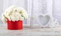 White roses in a red round box and a white photo frame close-up. Royalty Free Stock Photo