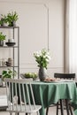 White roses in vase next to cookies on plate and apples in bowl on round table