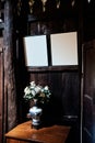 White roses in a vase on a wooden table with photo frames on the wooden wall, Wonderful antique living room decoration Royalty Free Stock Photo