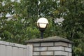 White round glass shining lantern on a brick wall of a fence on an evening street Royalty Free Stock Photo