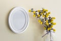 White round oval frame with yellow summer plants in glass vase