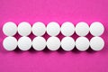 White round pharmaceutical pills on pink background