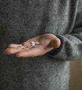 White round pill in the palm. Man`s hand in sweater. Royalty Free Stock Photo