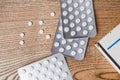 White round pills in aluminum packaging and white box of pills on a wooden table, copy space