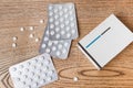 White round pills in aluminum packaging and white box of pills on a wooden table, copy space Royalty Free Stock Photo
