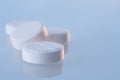 White round pills on a blue mirror surface with copy space, close up. Medicines on glass lit by the morning sun