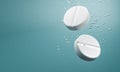 White round pills falling in water