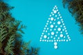 White round pills, laid out in shape of Christmas tree with spruce or thuja branch on light blue background. Copy space Royalty Free Stock Photo