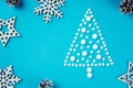 White round pills, laid out in shape of Christmas tree with wooden snowflakes and pine cones on light blue background Royalty Free Stock Photo