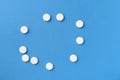 White round pills scattered on a blue background. Medical pharmacy concept Royalty Free Stock Photo