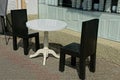 A white round plastic table and two black chairs stand on the sidewalk Royalty Free Stock Photo